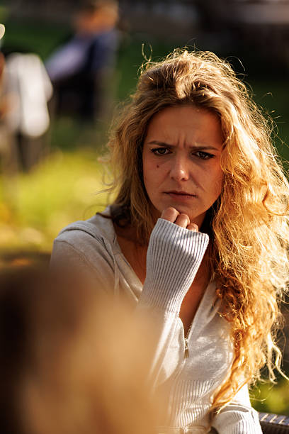 istock Thoughtful young woman in park during sunny afternoon engaging in deep conversation with friends in relaxed outdoor setting 2236625344