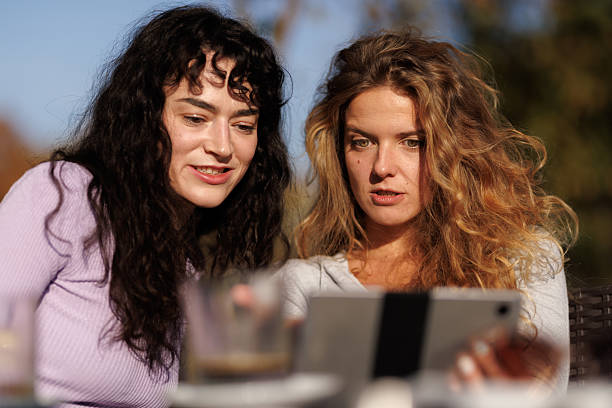 istock Friends enjoying a sunny afternoon outdoors while using a tablet to share laughs and explore content together 2236625363