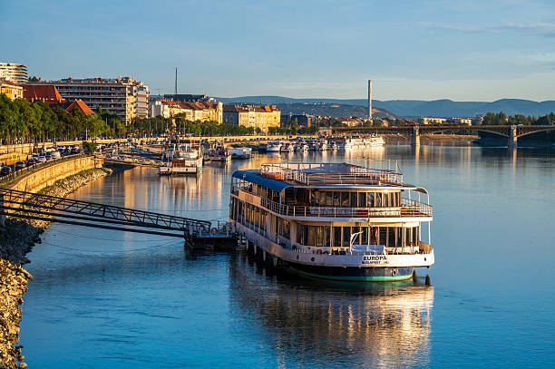Budapest, Central Hungary - September 18, 2025: Sunrise over the Danube River in Budapest, with a docked cruise ship and the city skyline in the background