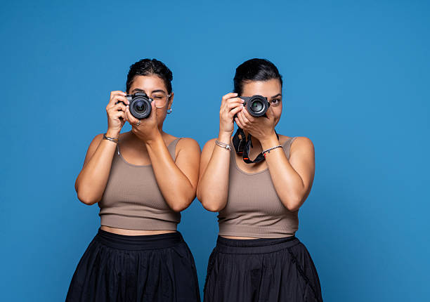 Portrait of two women photographers standing side by side, holding professional cameras and looking into the lens.