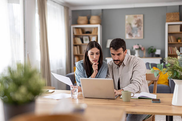 istock Focused couple reading documents on laptop at home. 2236641170