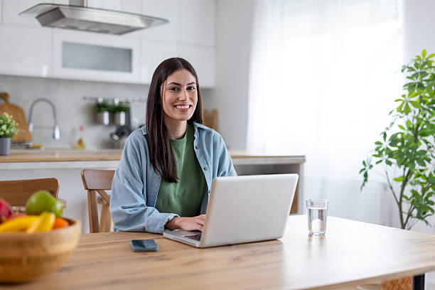 istock Cheerful woman working on laptop at a cozy kitchen table 2236641194