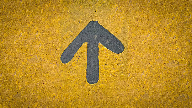istock rustic Bold gray up arrow on a rough yellow wall conveys direction, guidance, and forward movement. The urban, street art feel highlights contrast, texture, and visual direction in a simple graphic sign. 2236642131