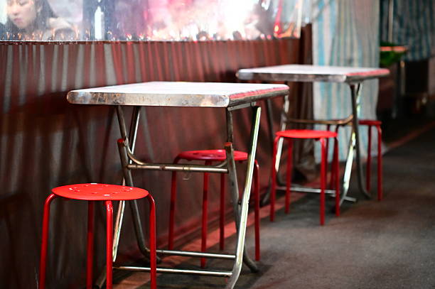 Taipei, Taiwan - Apr. 04, 2025: Candid night market dining furniture showing weathered metal frame tables with red round stools, authentic worn surfaces in genuine Taiwan street setting.