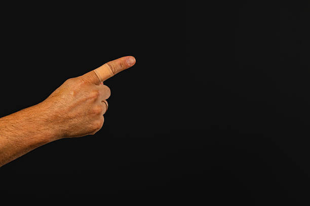 Hand pointing towards an unseen object against a dark background