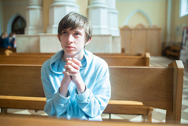 istock a 13 year old catholic boy is praying in a church 2236652217