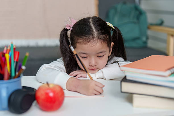 istock Child Writing in Notebook with Apple on Desk 2236653115