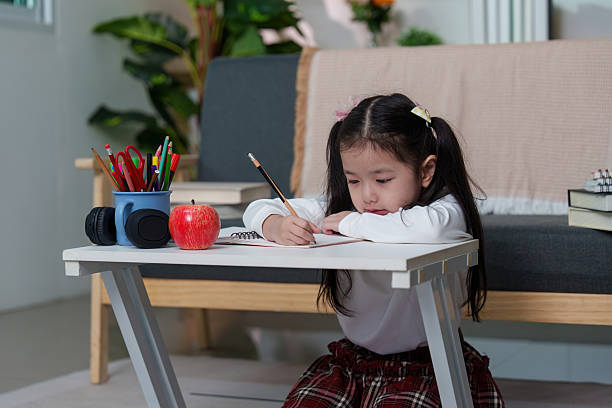 istock Young Girl Concentrating on Homework with Apple and Notebooks 2236653142