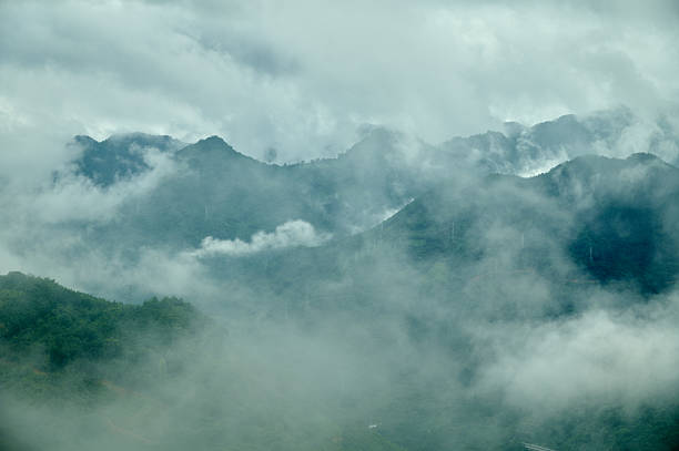 Green mountains rising through a thick layer of fog and clouds, creating a moody landscape