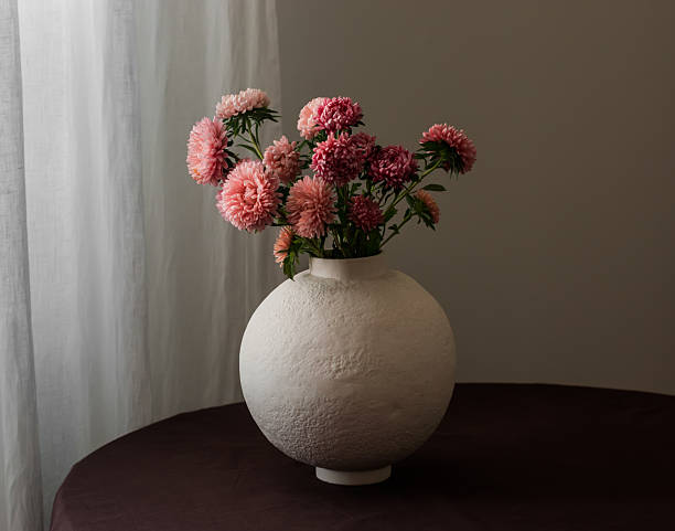 Bouquet of asters in a ceramic vase on a round table with a brown tablecloth
