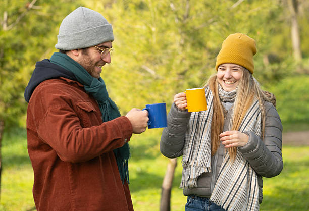istock Young couple smiling and drinking hot beverages outdoors in autumn 2236659667