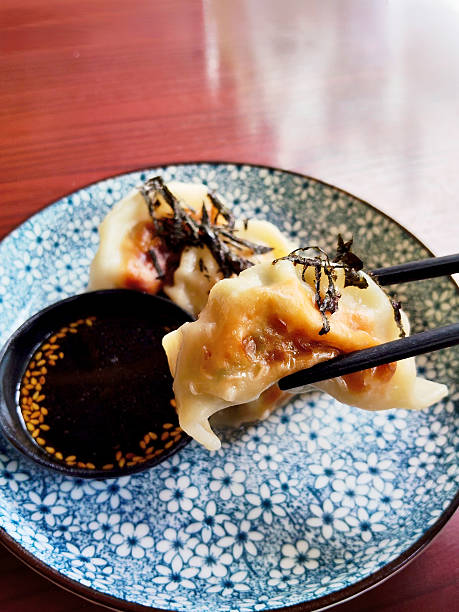 istock Crispy Pan-Fried Japanese Gyoza Dumplings Held by Black Chopsticks 2236660855