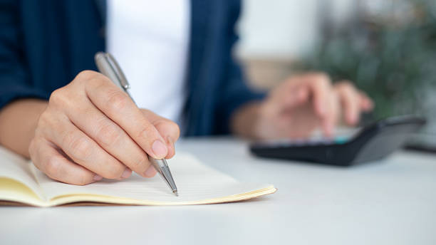 istock Handwriting notes with a pen while using a calculator, business accounting, financial planning, tax calculation, budget management, and economic analysis concepts for finance and office work. 2236662384