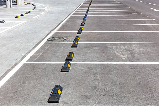 istock empty parking lot with white road marking and black rubber car stoppers. 2236666545