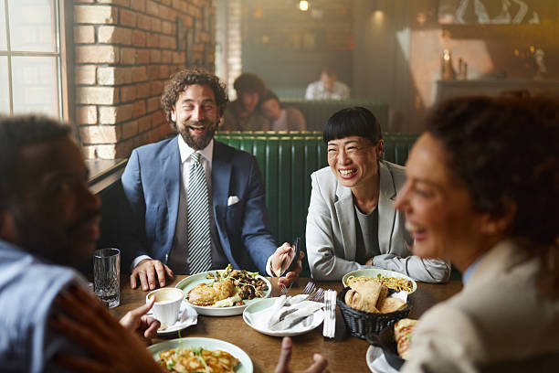 Team of cheerful entrepreneurs communicating while having brunch on a break in a restaurant.
