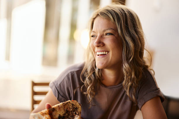 Portrait of happy woman day dreaming while eating pizza for a meal at home. Copy space.