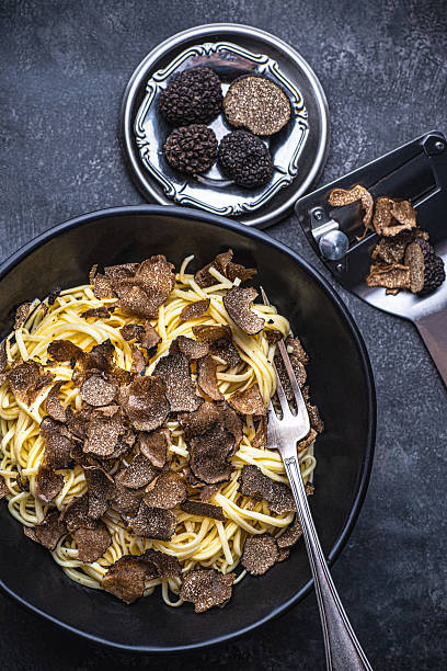 Black truffle pasta Tajarin. Black rustic table, magical autumn light, top view. Autumn gourmet cuisine of Piedmont, Northern Italy, Spain and France, close up