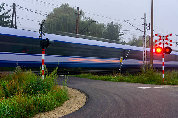 Passenger train passes railway crossing with red warning light, long exposure, motion blur, rail transport, safety, railway infrastructure, travel.