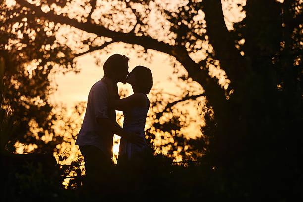 Affectionate couple kissing during romantic moment in nature at sunset. Copy space.