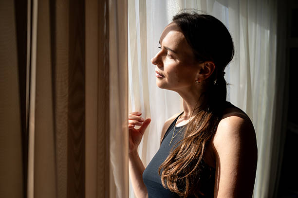 istock Thoughtful woman looking out the window in sunlight, cozy interior 2236670711
