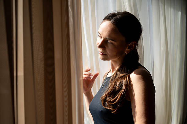 istock Thoughtful woman looking out the window in sunlight, cozy interior 2236670757