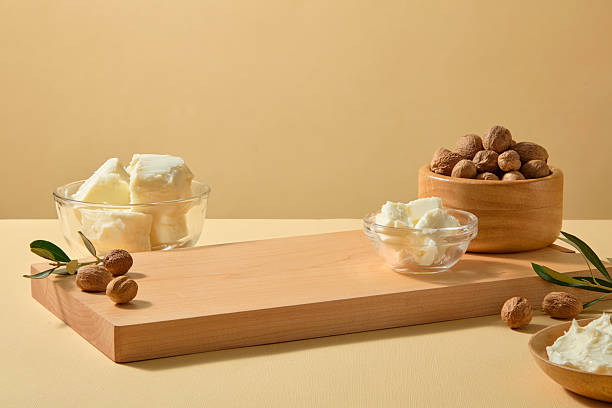 istock Rustic wood tray filled with raw shea butter, surrounded by smooth nuts on a beige background. Blank space for product text, branding or editorial layout. 2236672835