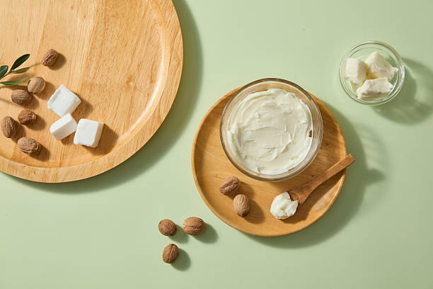 istock Soft daylight highlights shea butter scoops, rustic spoon and scattered nuts on pale green background, leaving blank area for overlay text or natural product marketing. Top view 2236672967