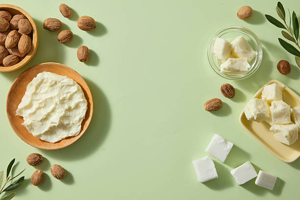 istock Clean tabletop with ivory shea butter chunks, smooth shea nuts and subtle green leaves placed artistically, conveying purity for eco-friendly skincare design. Top view, copy space 2236672971