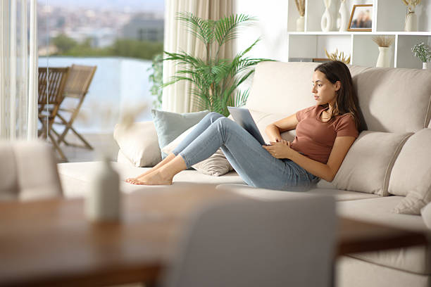 istock Woman using laptop seated on comfortable couch 2236674412