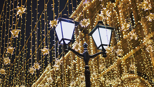 Street lamp illuminating christmas decorations hanging above a street