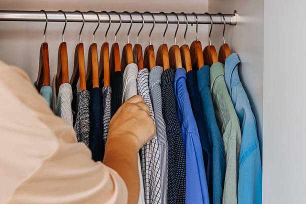 istock Hand choosing shirt from organized wardrobe with hangers 2236676498