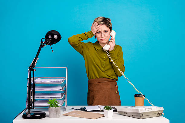 istock Stressed businesswoman expressing stress while on a phone call in a retro-style office setup with vibrant blue background 2236677447
