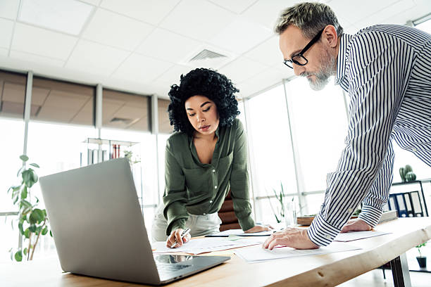 istock Professional coworkers collaborating over documents at a modern workspace desk, focusing on project analysis and teamwork 2236677557