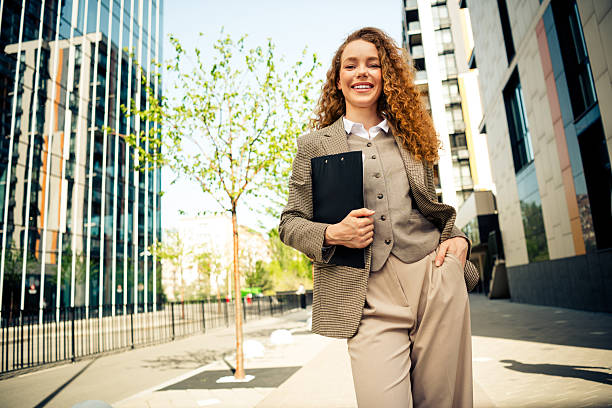 istock Confident female professional walking outdoors in an urban setting holding a clipboard on a bright sunny day 2236678083