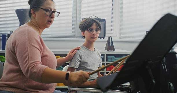 istock Talented Boy Playing Drums During Percussion Class. Female Teacher Teaching Young Musician 2236682639