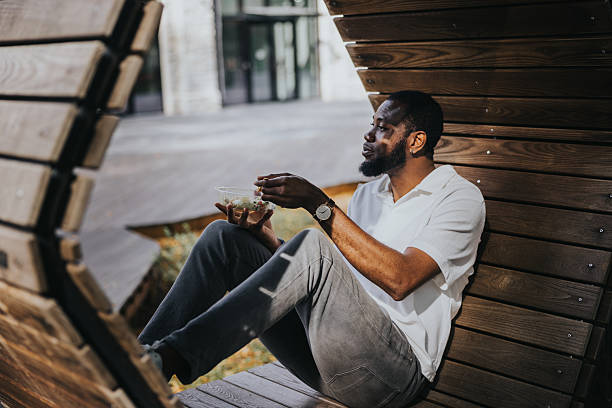 istock Black man eats take away salad in the public park during lunch 2236682814