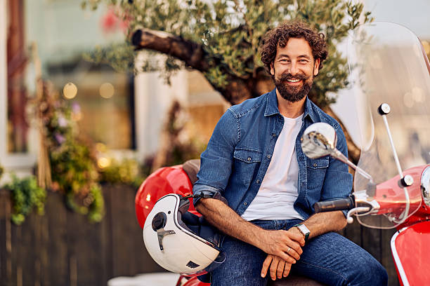 istock Smiling Man Sitting on a Scooter in a Vibrant Urban Outdoor Setting 2236683317