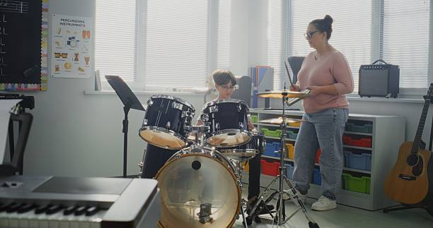 istock Primary School Boy Practicing Drums in Modern Music Class. Female Teacher Educating Talented Child 2236683359