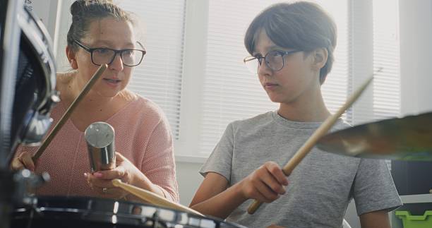 istock Talented Boy Playing Drums During Percussion Class. Teacher Teaching Young Musician to Play Drum Kit 2236684404
