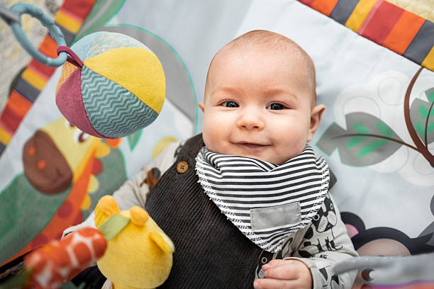 istock Adorable baby lying on activity mat playing with toys at home smiling 2236687593