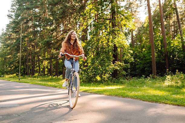 istock A cheerful woman rides a bicycle in a sunny forest. 2236687885