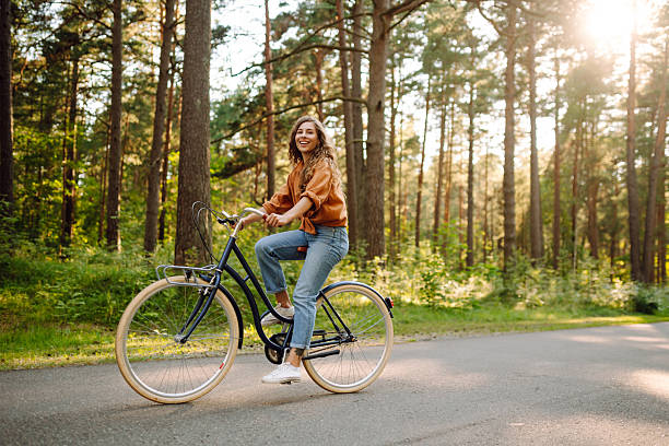 istock A cheerful woman rides a bicycle in a sunny forest. 2236687886