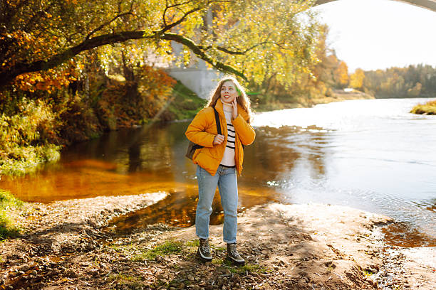 istock A beautiful hiker in a yellow jacket and carrying a backpack walks along a hiking trail along the river. 2236688747
