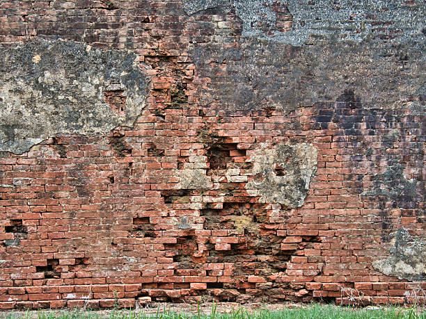 istock Old weathered brick wall texture background - A close-up full frame of a weathered brick wall with sections of damaged mortar, exposing a rough and textured surface. 2236689611