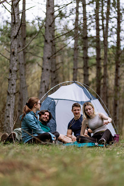 istock Friends enjoying a camping experience in a forest clearing during late afternoon, engaging in conversation near their tent and surrounded by nature 2236693074