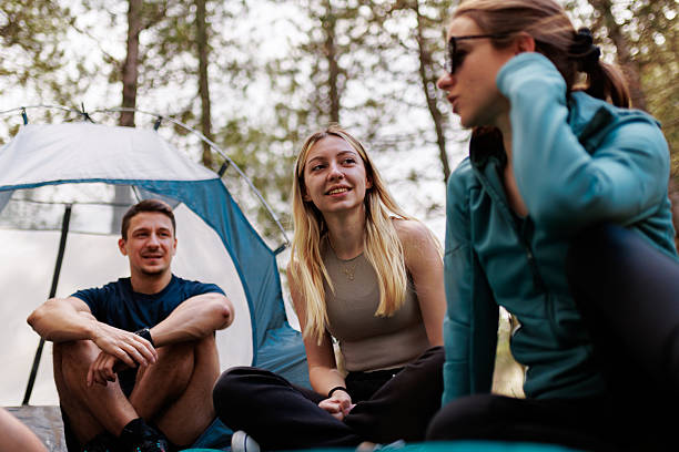 istock Group of friends enjoying a relaxing camping trip together in a forest setting, sharing stories around a tent on a sunny day 2236693088