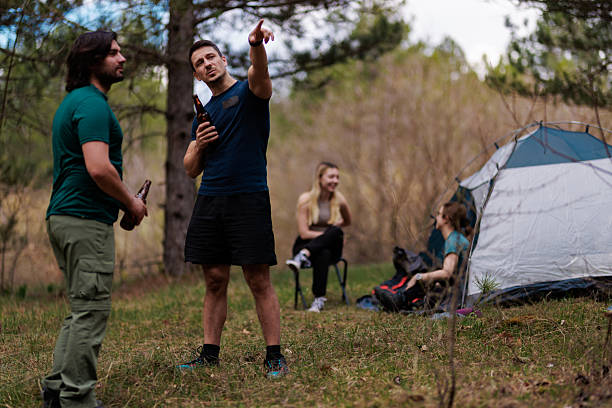 istock Friends enjoy a camping trip in the woods while sharing drinks and laughter on a sunny day 2236693110