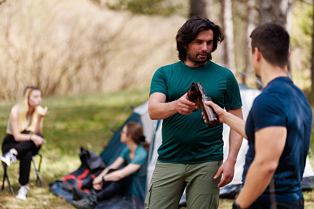 istock Friends enjoying a camping trip while gathered around tents in a forest during daytime, engaging in activities and sharing drinks in nature 2236693111