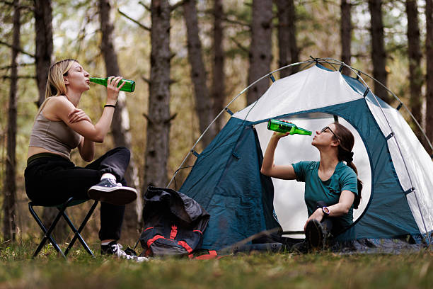 istock Friends enjoying refreshments while camping in a forest with a tent on a sunny day, creating memorable outdoor experiences together 2236693112