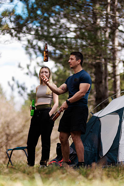 istock Camping adventure with friends enjoying drinks and laughter in a serene forest setting during a sunny afternoon 2236693122